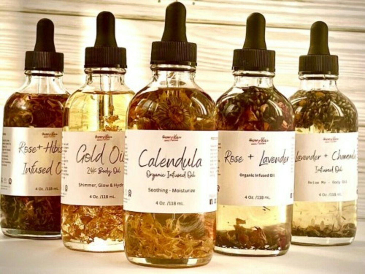 Tropfflaschen mit Körperöl und Botanicals auf rustikalem Holz.